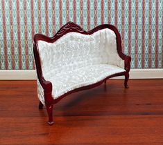 a miniature couch sitting on top of a hard wood floor next to a wallpapered wall