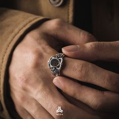 a close up of a person's hand with a ring on their finger, wearing a jacket