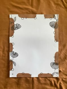 a piece of paper with flowers on it sitting on top of a brown sheet of cloth