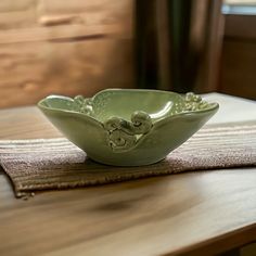 a green bowl sitting on top of a wooden table