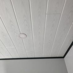 a ceiling with white painted wood planks and a round hole in the center for lighting