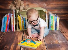 a baby is playing with a book on the floor in front of bookshelves