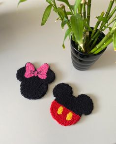 two crocheted mickey and minnie mouse magnets next to a potted plant