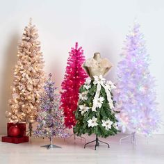 three different types of artificial christmas trees in front of a white wall with presents on it