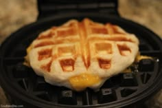 a waffle topped with melted cheese on top of a black pan