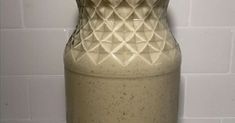 a white vase sitting on top of a counter next to a tiled wall in a kitchen