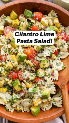 a wooden bowl filled with pasta salad on top of a table