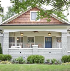 the front porch of a house with two chairs on it and green grass in front