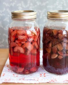 two jars filled with fruit sitting on top of a table