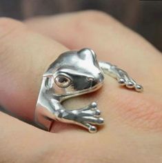 Embrace whimsical charm with this delightful Silver Frog Ring. Crafted with attention to detail, this ring features an adorable frog design, perfect for adding a fun, nature-inspired touch to your outfit. The sleek silver finish makes it versatile for everyday wear or special occasions, while the lightweight design ensures all-day comfort. Frog Symbolism, Cheap Trendy Jewelry, Frog Ring, Open Cuff Ring, Frog Jewelry, Leg Chain, Turning Point, Finger Rings, Ear Cuffs