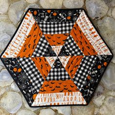 an orange and black hexagonal patchwork piece on some rocks with the words halloween written across it