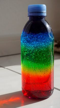 a bottle that is sitting on the floor with some water in it and rainbow colors