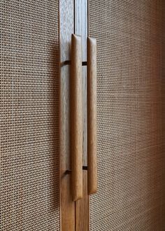 two wooden handles on the side of a wall with woven fabric behind them and another door handle