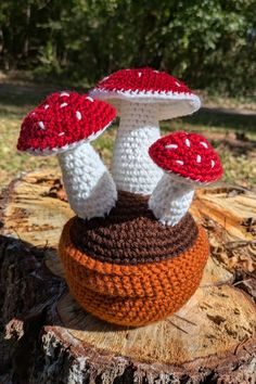 two crocheted mushrooms sitting on top of a tree stump