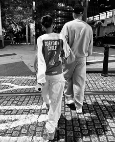 two people are walking down the sidewalk in black and white, one is wearing a shirt that says cowboys circle