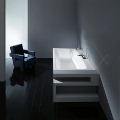 a chair sitting next to a white sink in a room with black floors and walls