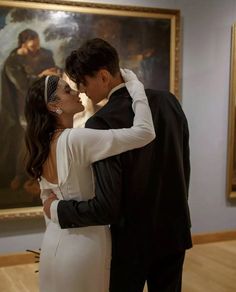 a man and woman kissing in front of a painting