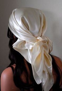 a woman with long hair wearing a white satin head scarf on top of her head