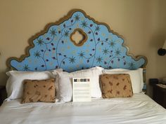 a bed with white sheets and blue headboard