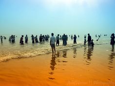 many people are standing in the water at the beach