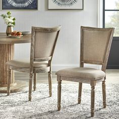 a dining room table with two chairs next to it and a rug on the floor