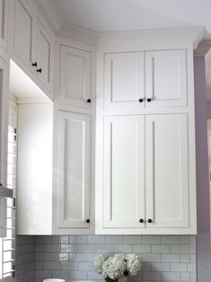 a kitchen with white cabinets and marble counter tops