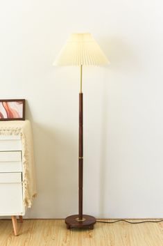 a floor lamp sitting next to a white dresser