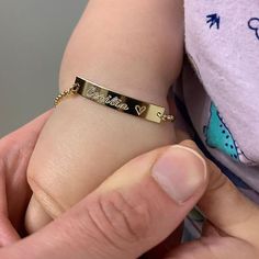 a person holding onto a gold bracelet with the word love written on it in cursive writing