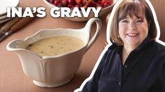 a woman sitting in front of a bowl of gravy next to a spoon