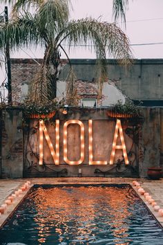 a neon sign that says nola in front of a pool