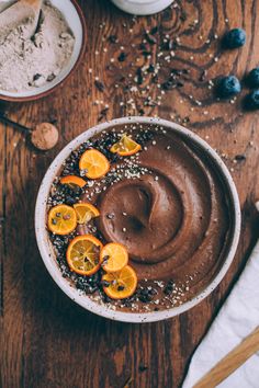 a bowl filled with chocolate and oranges on top of a wooden table next to two bowls