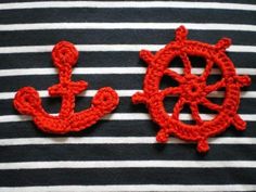 two red crocheted anchors and a steering wheel on a black and white striped shirt