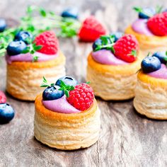 small pastries with berries and blueberries are on a wooden table, ready to be eaten