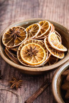 orange slices and star anise in a bowl on a wooden table with cinnamon sticks