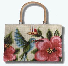 a handbag with flowers on it and a bird in the middle is hanging from a wooden handle