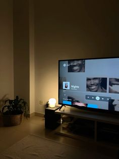 a flat screen tv sitting on top of a wooden stand in a living room next to a potted plant