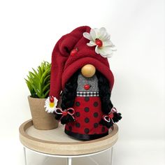 a small potted plant with a red hat on it and a lady bug doll