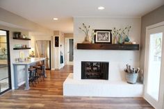 a living room filled with furniture and a fire place in the middle of a kitchen