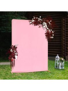 a pink backdrop with white flowers and greenery on the side for an outdoor ceremony