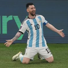 a soccer player sitting on the ground with his arms out and hands outstretched in celebration