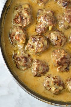 meatballs and gravy are cooking in a skillet