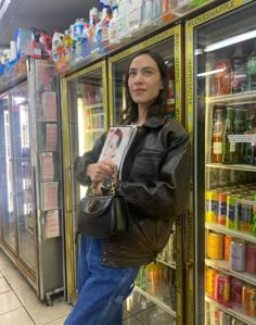 a woman standing in front of a refrigerator holding onto a bag and looking at the camera