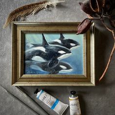 an oil painting of two orca's in a frame next to some other items