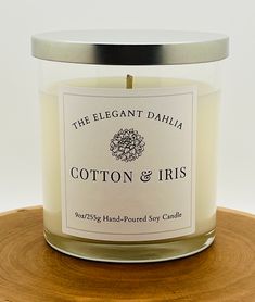 the elegant dahla cotton & iris candle is on a wooden stand with a metal lid