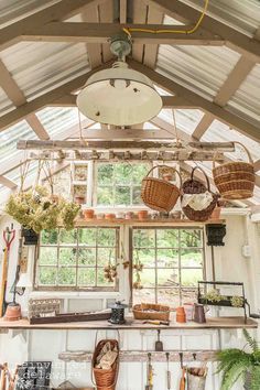 the inside of a greenhouse with lots of potted plants and baskets hanging from the ceiling