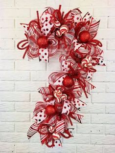 a red and white christmas wreath hanging on a brick wall