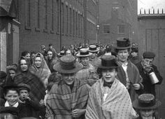 an old black and white photo of people walking down the street with hats on their heads