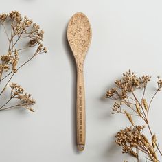 a wooden spoon sitting on top of a table next to some dried flowers and plants