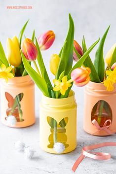 three painted jars with flowers in them