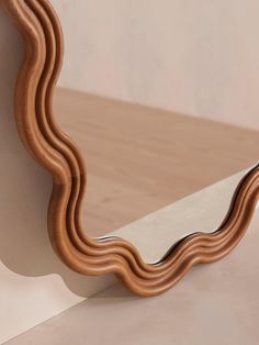 the curved mirror is made out of wood and has a metal handle on it's side